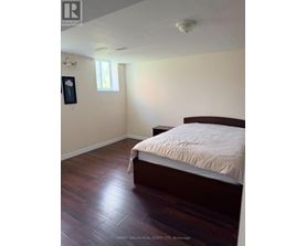 A bedroom with a bed, wooden floors, and a window.