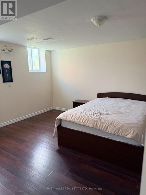 A bedroom with a bed, wooden floors, and a window.