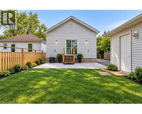 A white house with a wooden fence and a green lawn in front.