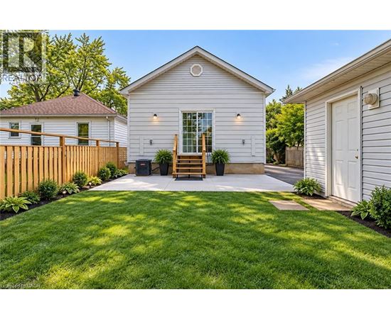 A white house with a wooden fence and a green lawn in front.