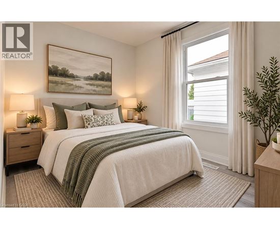 A bedroom with a large bed, two lamps, and a painting on the wall.