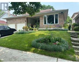 A house with a front yard and a black car parked in the driveway.