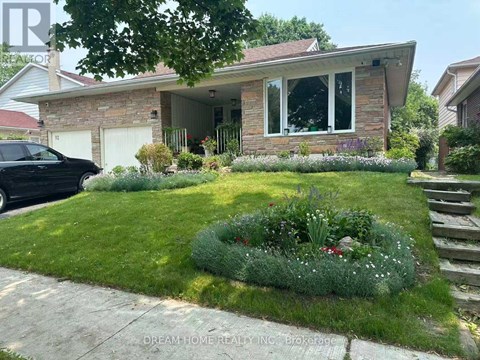 A house with a front yard and a black car parked in the driveway.