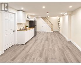 A well-lit, spacious kitchen with white cabinetry and a wooden floor.