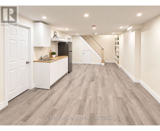 A well-lit, spacious kitchen with white cabinetry and a wooden floor.