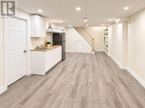 A well-lit, spacious kitchen with white cabinetry and a wooden floor.