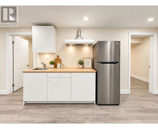 A modern kitchen with white cabinets and a stainless steel refrigerator.