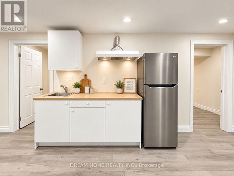 A modern kitchen with white cabinets and a stainless steel refrigerator.