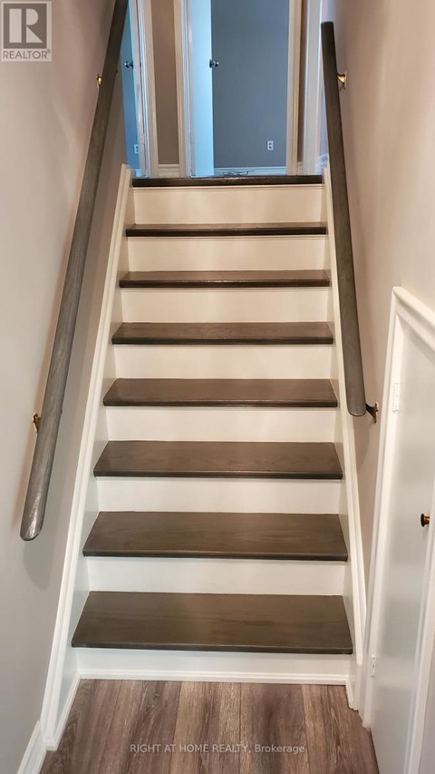 A set of stairs with a metal handrail and wooden steps leading to a door.