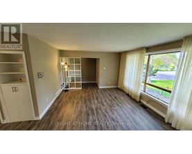 A room with a wooden floor and a large window with curtains.