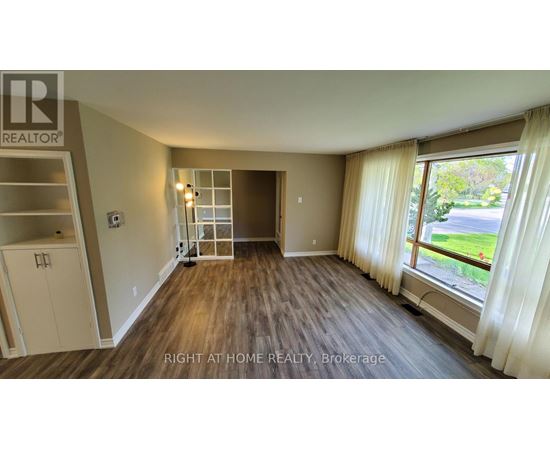 A room with a wooden floor and a large window with curtains.