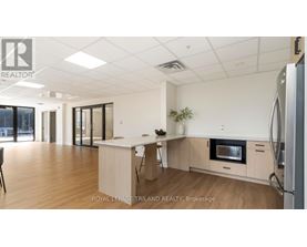 A kitchen with a refrigerator, microwave, and a dining table with chairs.