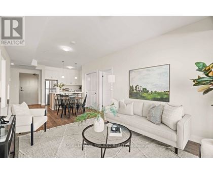 A living room with a white couch, a coffee table, and a painting on the wall.