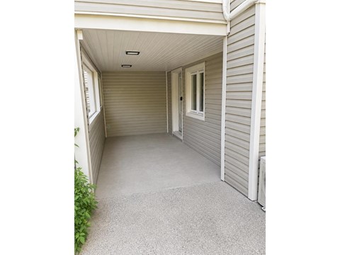A small, white, enclosed porch with a grey carpet.