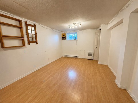 A room with wooden flooring and a window with blinds.