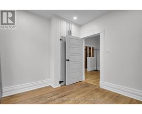 A white door in a room with wooden floors and white walls.