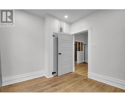 A white door in a room with wooden floors and white walls.