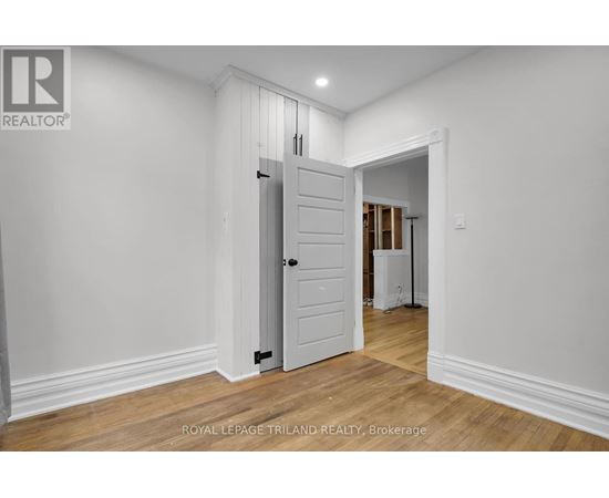 A white door in a room with wooden floors and white walls.