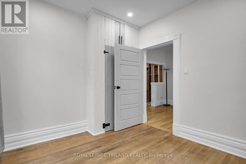 A white door in a room with wooden floors and white walls.