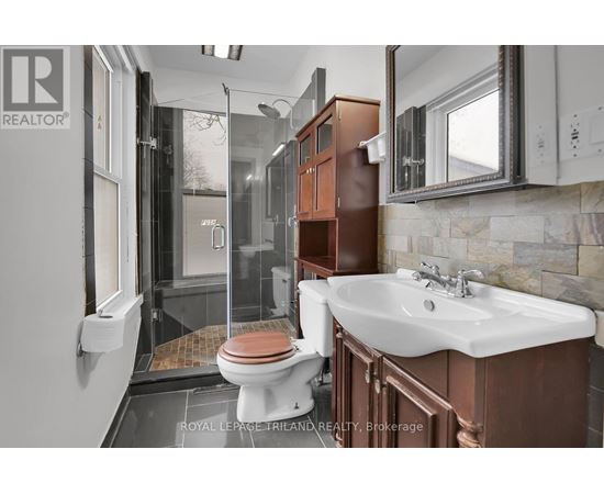 A bathroom with a toilet, sink, and mirror.