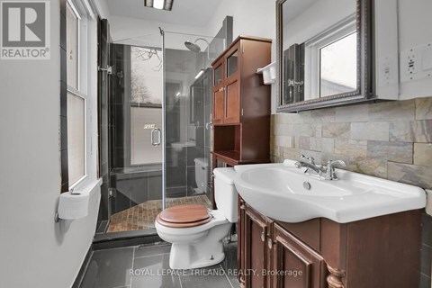 A bathroom with a toilet, sink, and mirror.