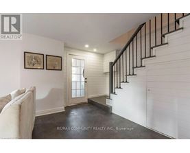 A white hallway with a staircase and two pictures on the wall.