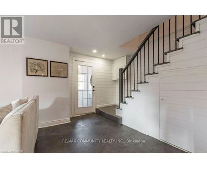 A white hallway with a staircase and two pictures on the wall.