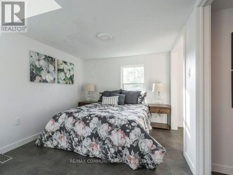A bedroom with a floral bedspread and two lamps on a table.