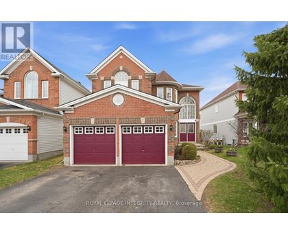 A large brick house with a red garage door is for sale.