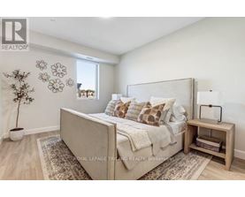 A bedroom with a large bed, a nightstand, and a plant.