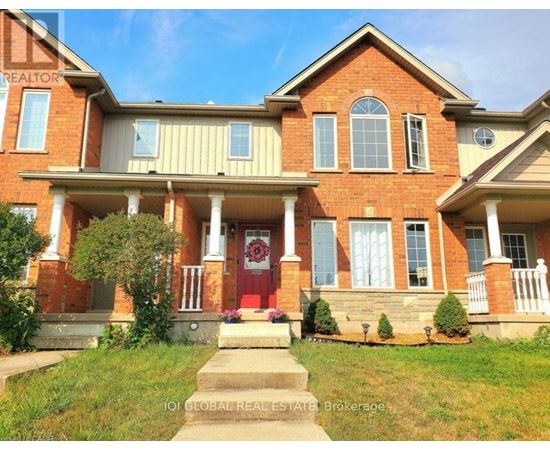 A red brick house with a red door and a sign that says "REALTOR" on the left side.