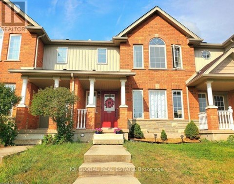 A red brick house with a red door and a sign that says "REALTOR" on the left side.