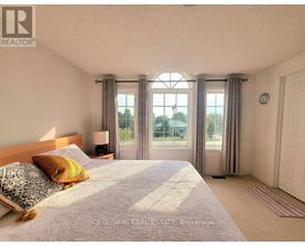 A bedroom with a large bed and a window with curtains.