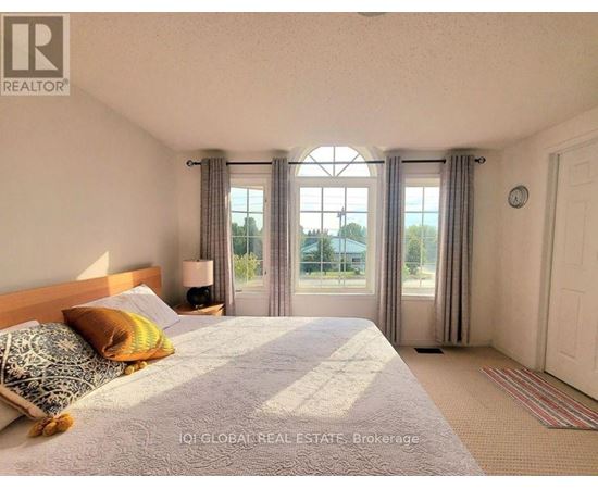A bedroom with a large bed and a window with curtains.