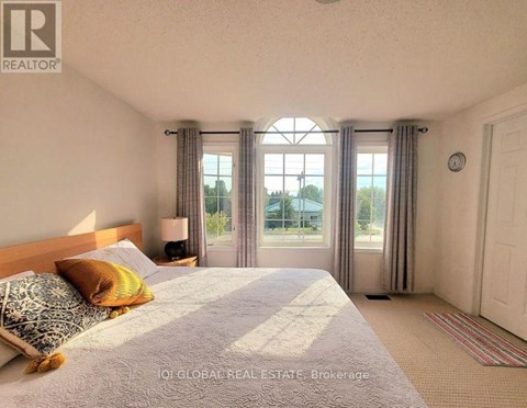A bedroom with a large bed and a window with curtains.