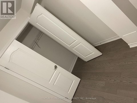A white door with a handle is in the middle of a room with a wooden floor.