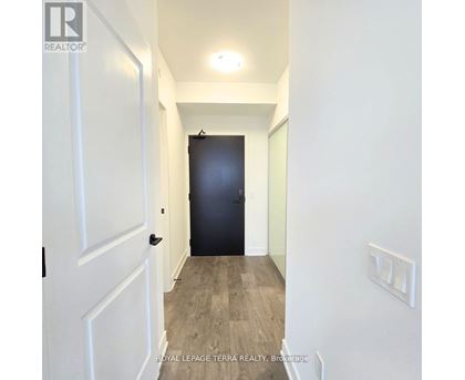 A hallway with a black door and white walls.