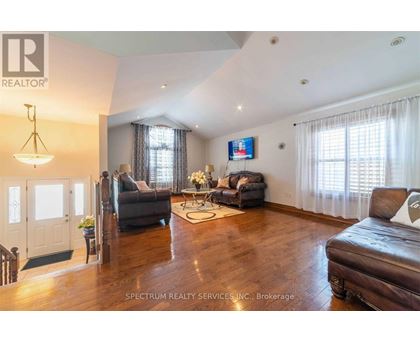 A living room with a brown leather couch and a television mounted on the wall.