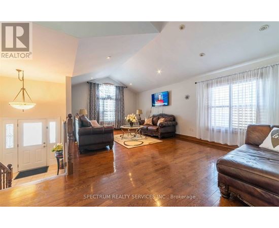 A living room with a brown leather couch and a television mounted on the wall.