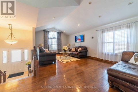 A living room with a brown leather couch and a television mounted on the wall.