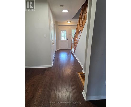 A hallway with wooden floors and a staircase.