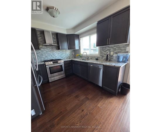 A kitchen with wooden floors and a stone backsplash.