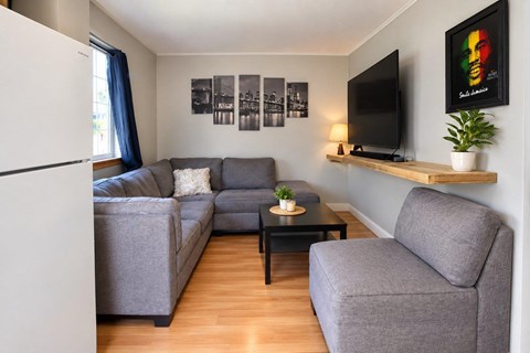 A living room with a grey couch, a black coffee table, and a television on a wooden shelf.
