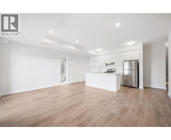 A spacious kitchen with wooden flooring and stainless steel appliances.