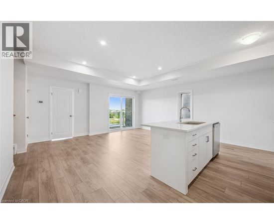 A spacious room with wooden flooring and white walls.