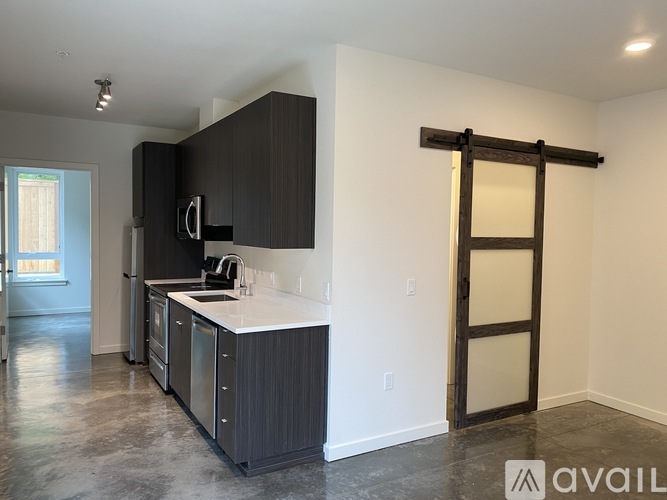 A kitchen with black cabinets and a white countertop is available for rent.