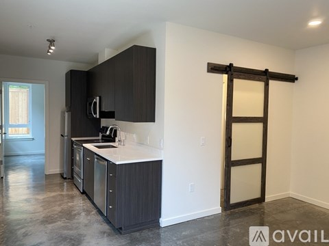 A kitchen with black cabinets and a white countertop is available for rent.