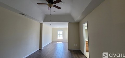 A spacious room with a ceiling fan and wooden flooring.