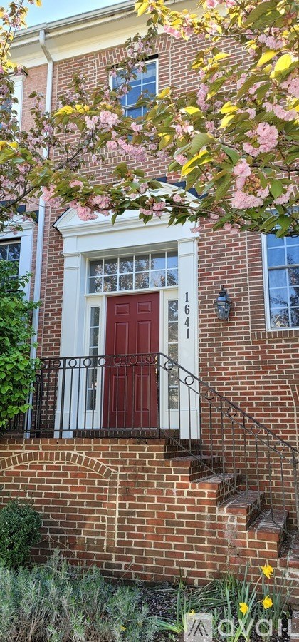 A red door is on the front of a brick building.