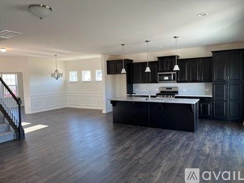 A spacious kitchen with black cabinets and a white island.